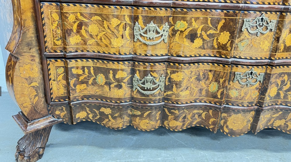 A Dutch walnut display cabinet featuring intricate floral marquetry inlay throughout, an arched glazed upper section, a shaped lower chest with drawers, and carved claw feet. View X