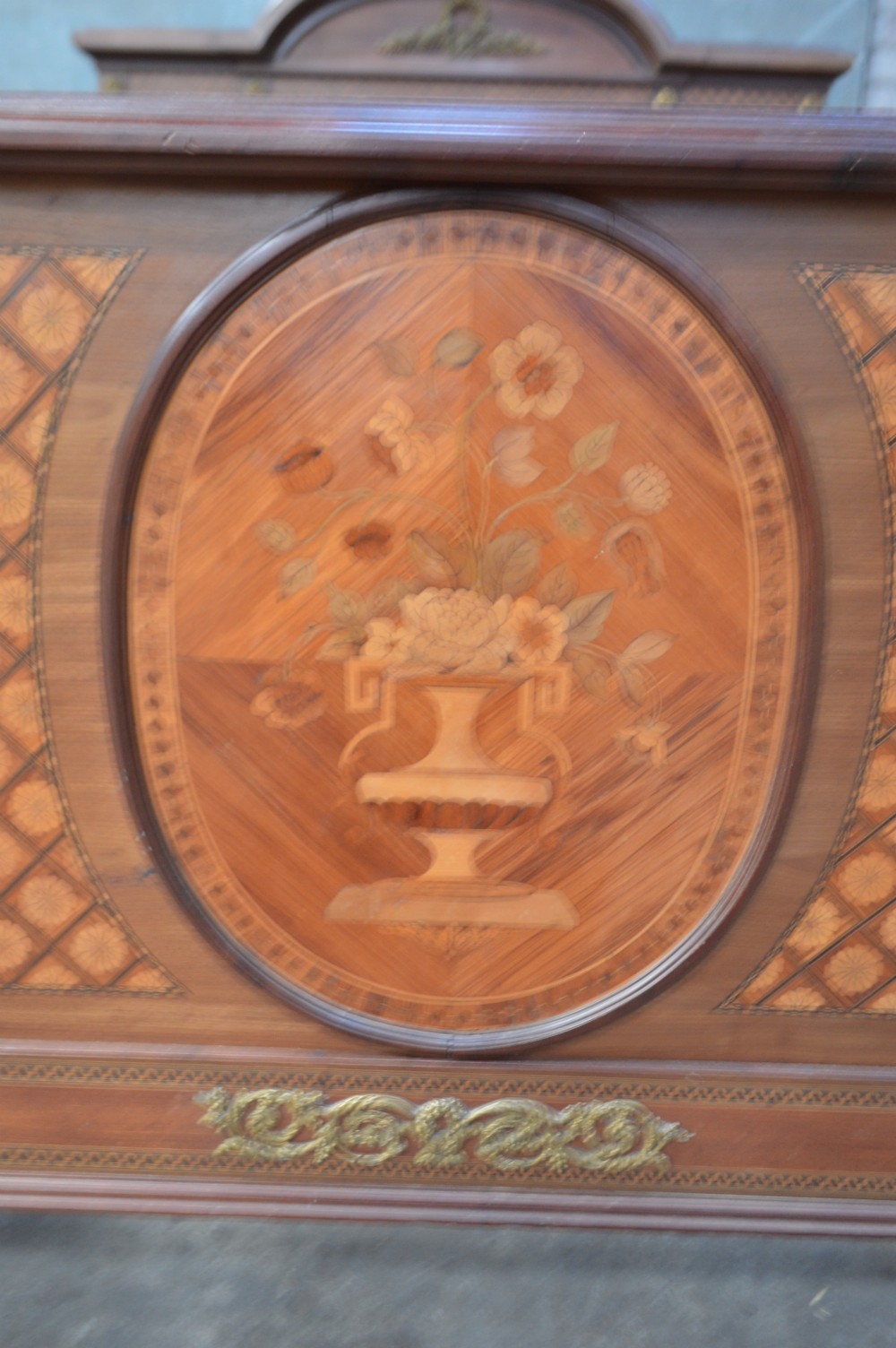 A French Louis XVI Revival wooden double bed featuring intricate floral marquetry paneling, trellis parquetry, curved footboard ends, and gilded metal mounts. View II