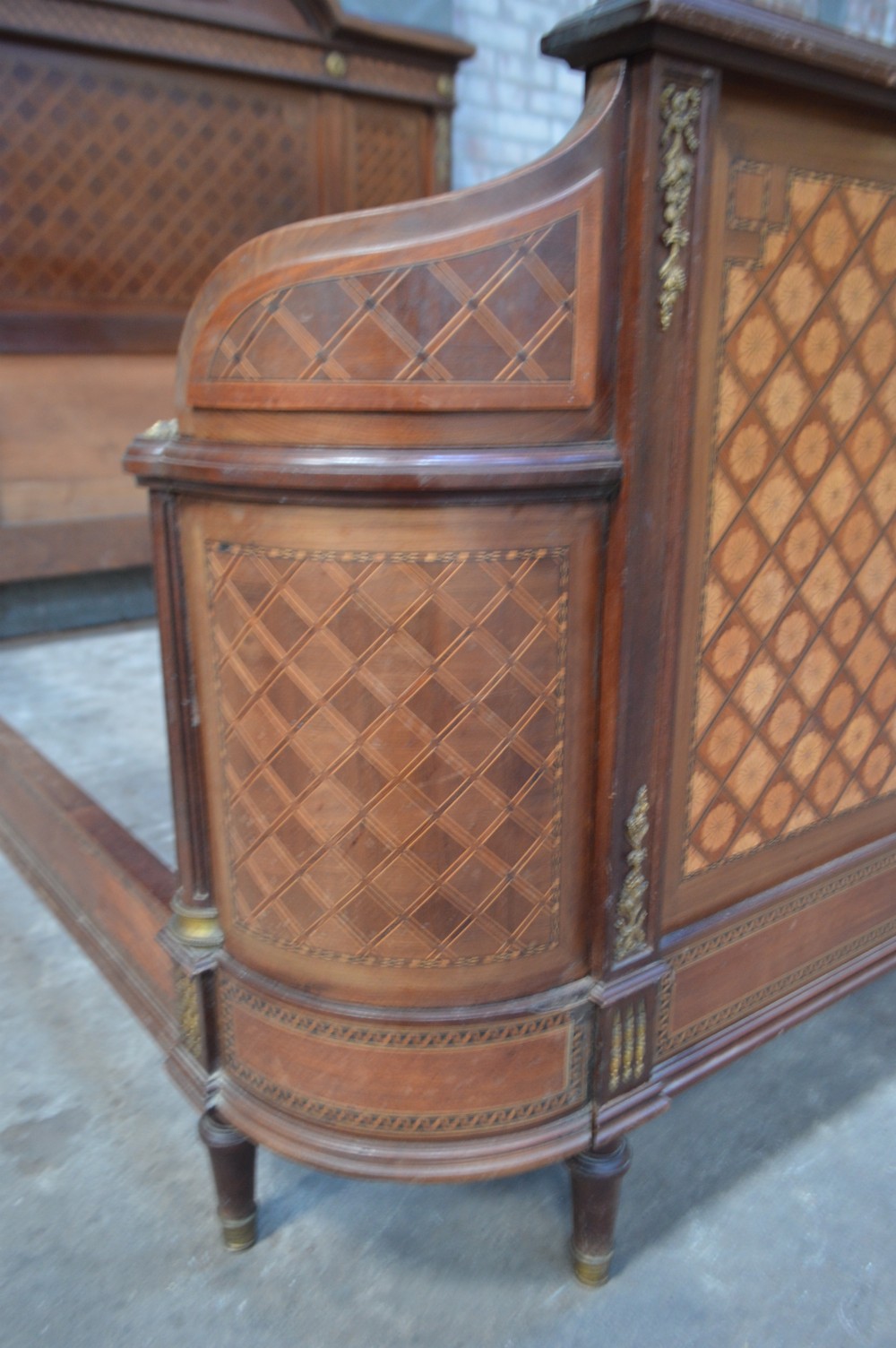 A French Louis XVI Revival wooden double bed featuring intricate floral marquetry paneling, trellis parquetry, curved footboard ends, and gilded metal mounts. View V