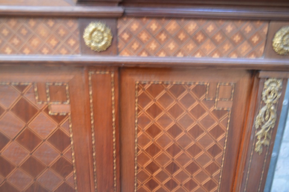 A French Louis XVI Revival wooden double bed featuring intricate floral marquetry paneling, trellis parquetry, curved footboard ends, and gilded metal mounts. View VI