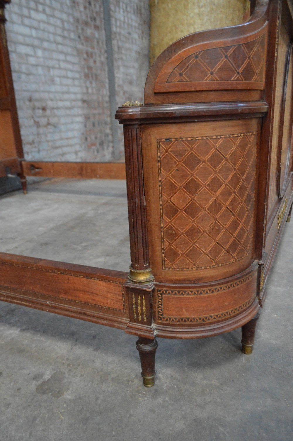 A French Louis XVI Revival wooden double bed featuring intricate floral marquetry paneling, trellis parquetry, curved footboard ends, and gilded metal mounts. View VIII