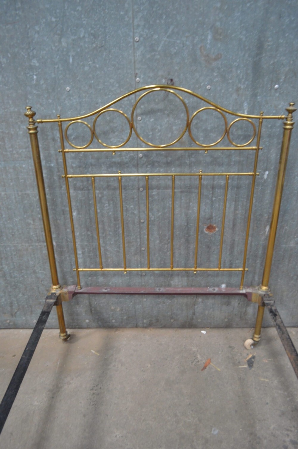 Victorian brass single bedstead featuring tubular brass posts with circular ring motifs, vertical spindles, and ceramic castors. View III