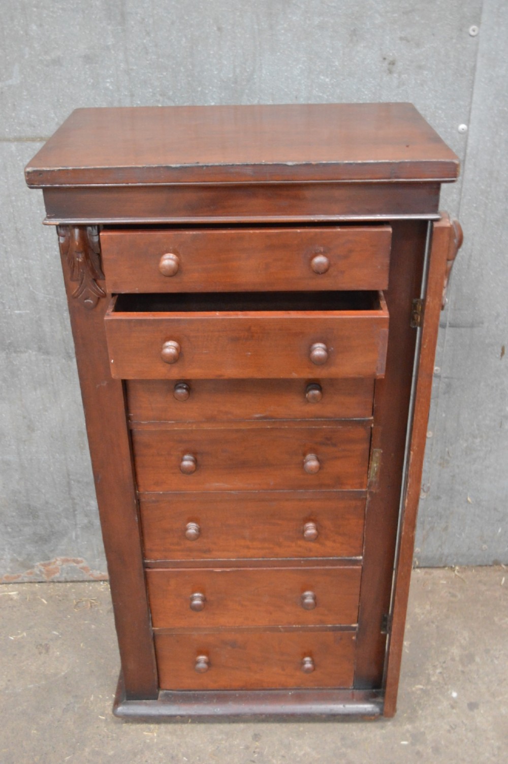 A tall, narrow Victorian mahogany Wellington chest featuring seven graduated drawers with turned wooden knobs and a hinged right-hand locking bar. View III