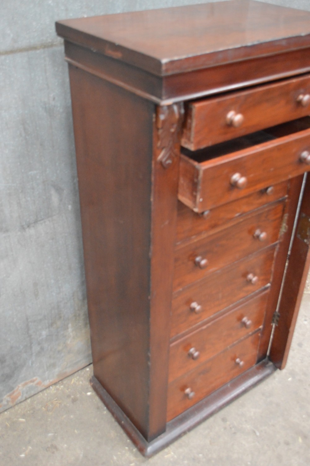 A tall, narrow Victorian mahogany Wellington chest featuring seven graduated drawers with turned wooden knobs and a hinged right-hand locking bar. View V