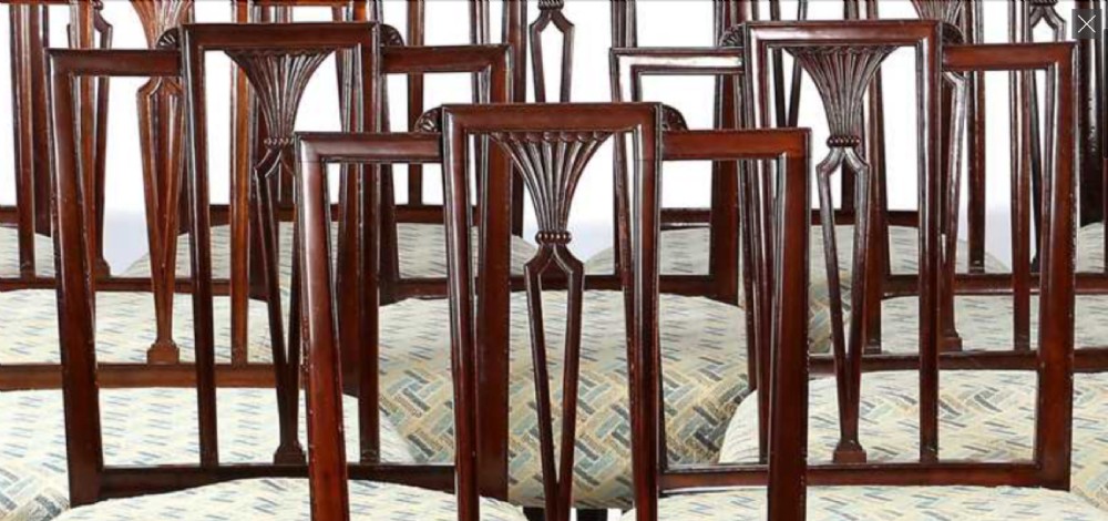 A set of twelve George III mahogany dining chairs featuring carved openwork back splats, patterned upholstery, and square tapered legs. View II