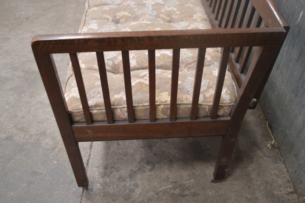 A 1920s oak day bed with vertical slatted back and side panels, fitted with a patterned floral cushion mattress. View II