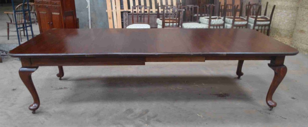 A large Victorian mahogany extending dining table with cabriole legs resting on castors.