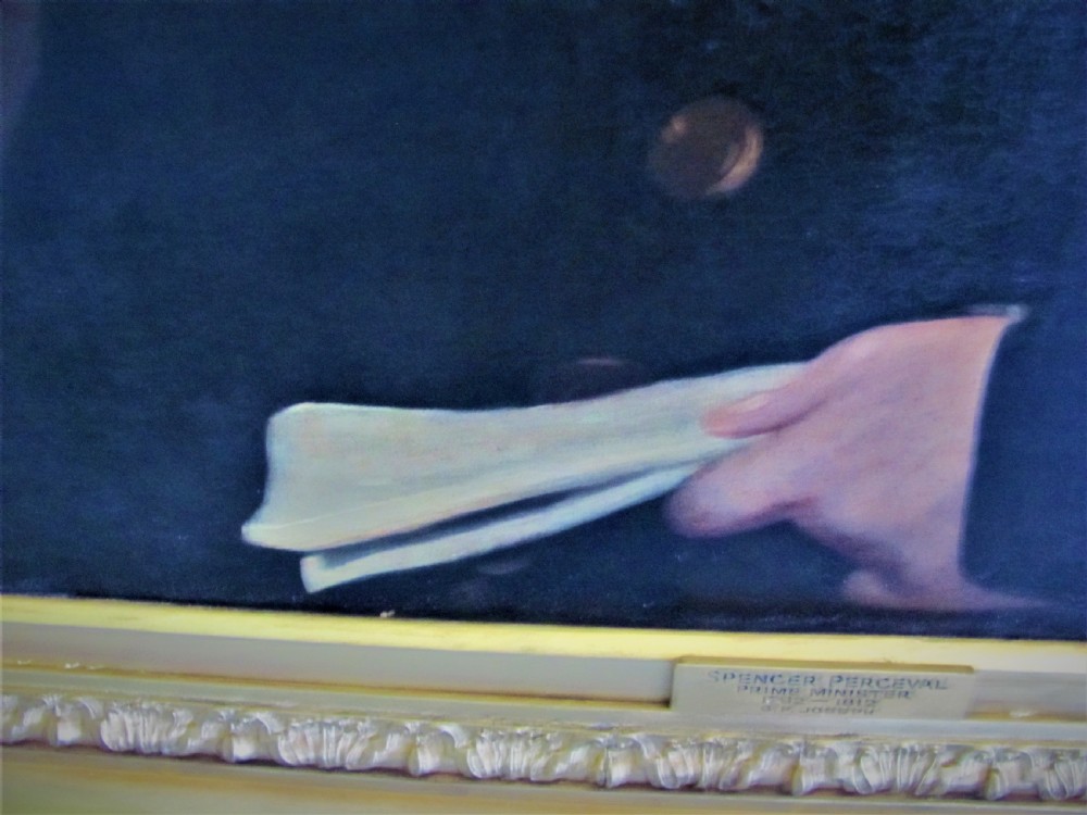 A 19th-century framed oil painting depicting a gentleman in a dark blue coat and white cravat set against a red draped backdrop. View V
