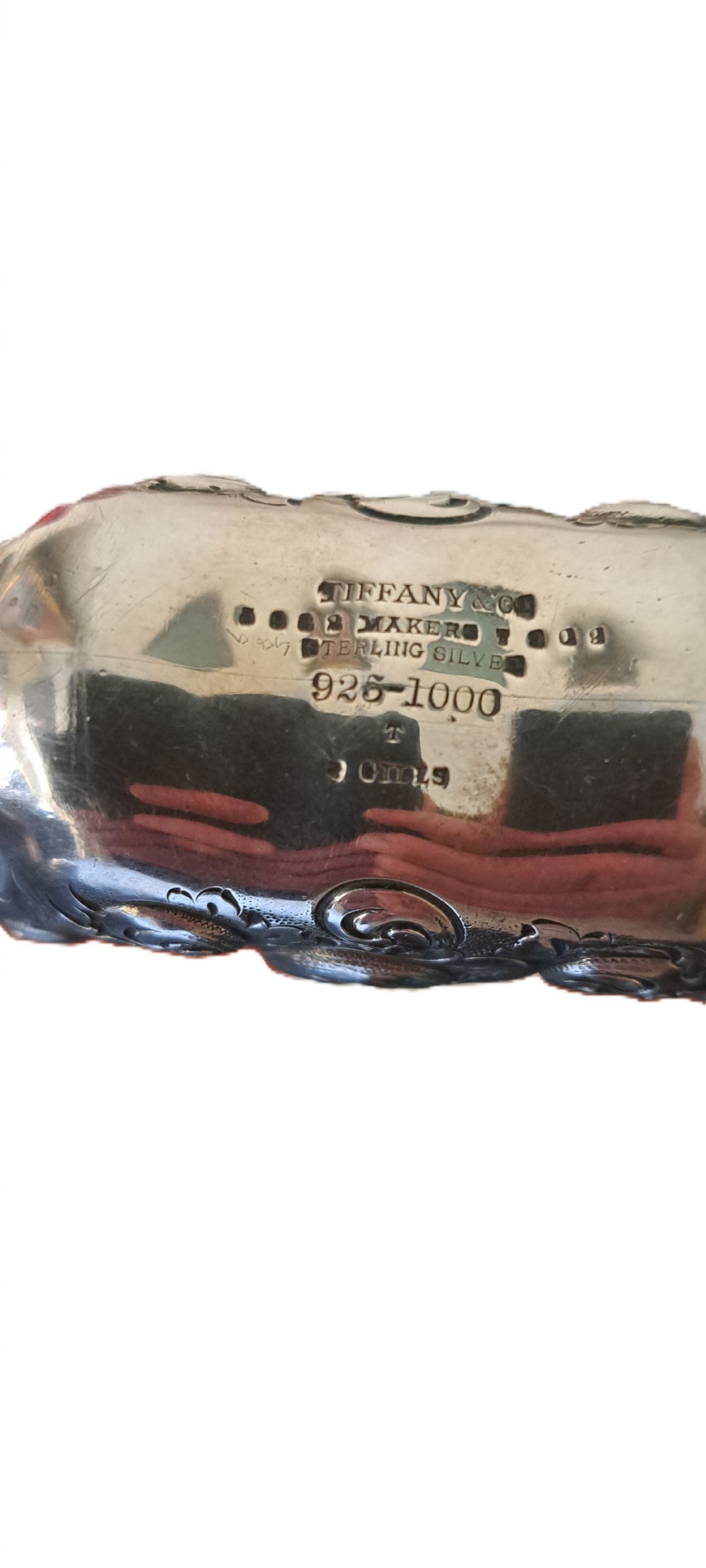 An antique sterling silver hip flask featuring repousse scrollwork, an engraved central monogram, and a silver cap. View VII