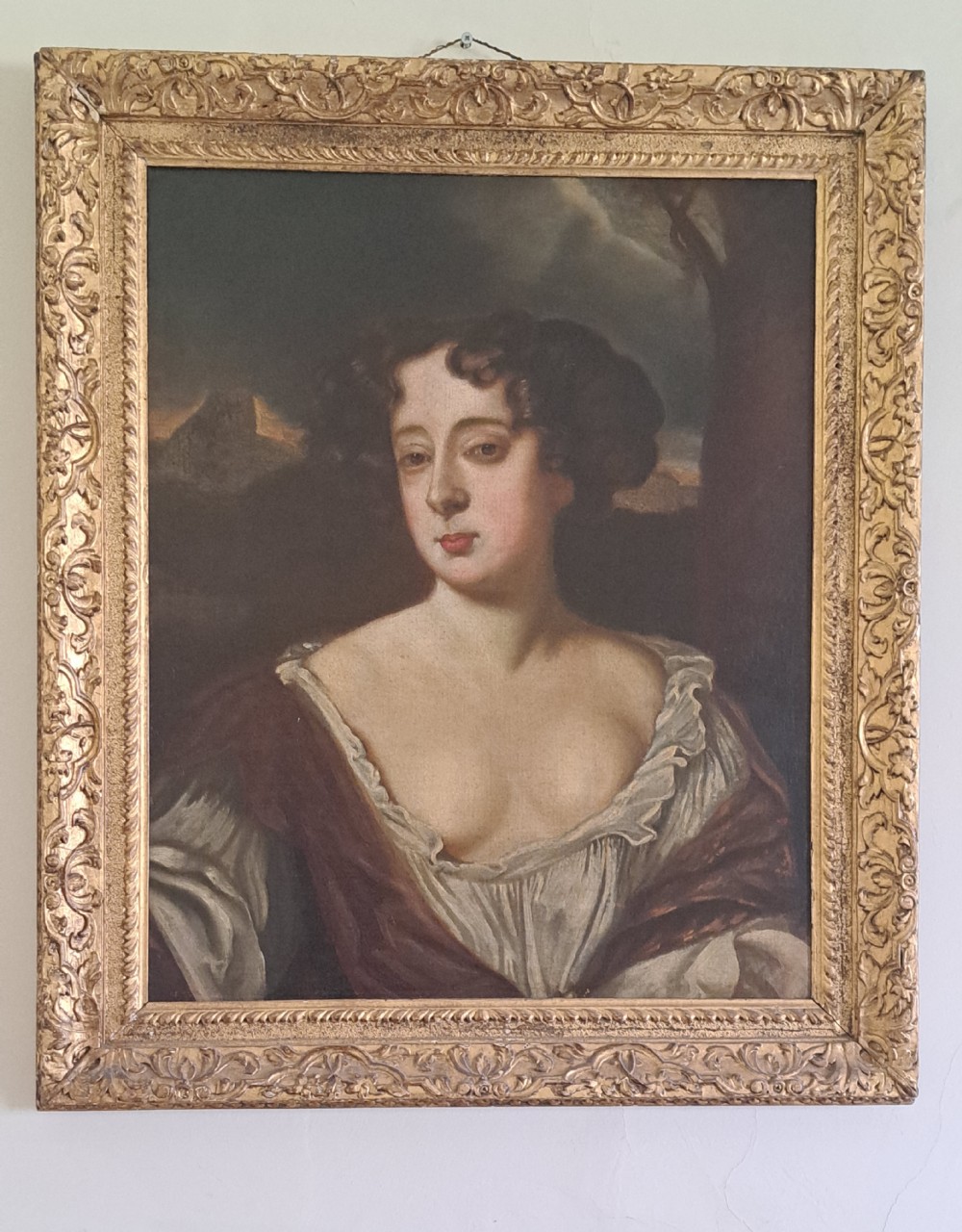 A 19th-century portrait painting of a woman with dark ringlets in a low-cut gown, framed in an ornate carved gilt frame.