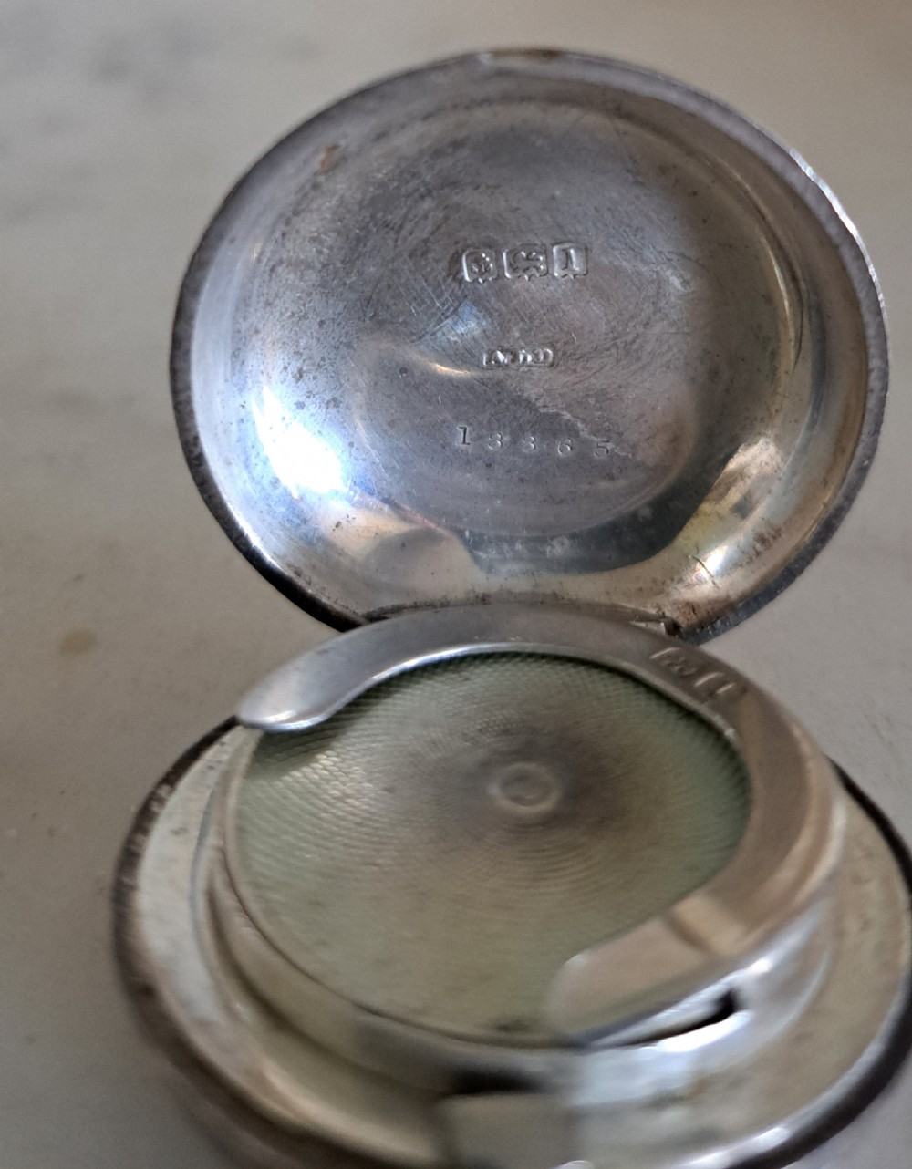 A circular Edwardian sterling silver single sovereign case featuring foliate scroll engraving and a central unengraved cartouche. View VI