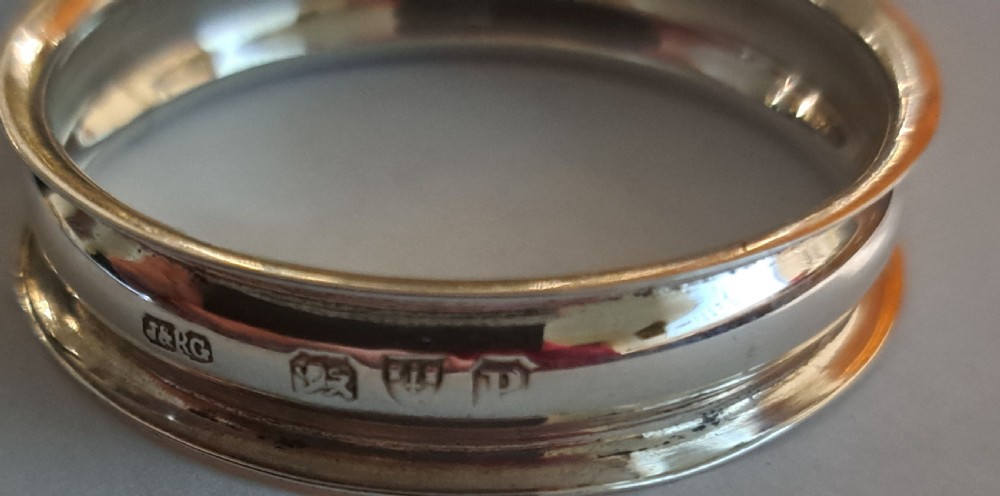 A set of six Victorian sterling silver napkin rings displayed inside a black fitted presentation box lined with silk and purple velvet. View VII