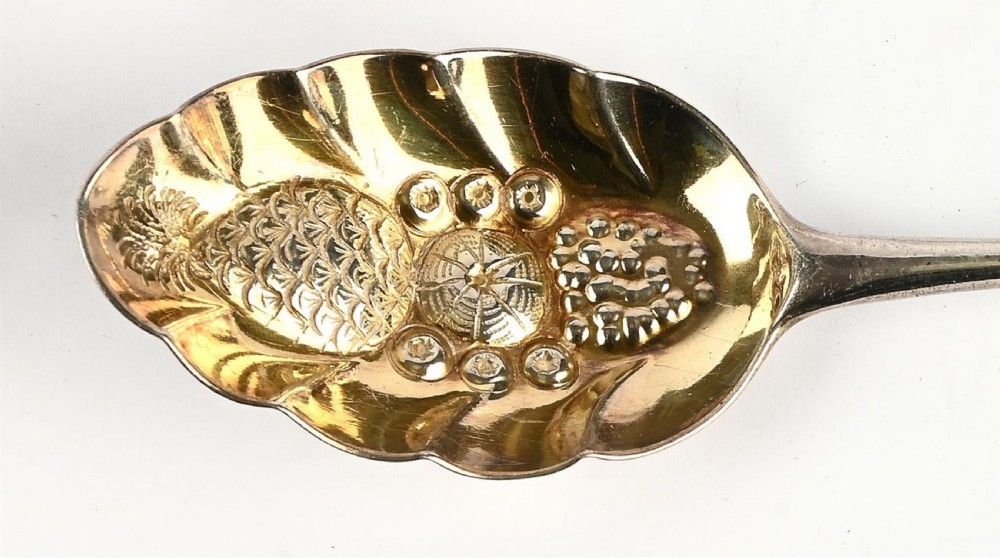 A pair of George III sterling silver berry spoons featuring bright-cut engraved handles and gilt repousse bowls embossed with fruit motifs. View III