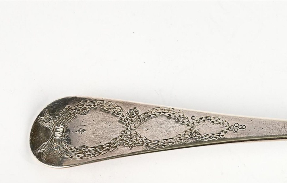 A pair of George III sterling silver berry spoons featuring bright-cut engraved handles and gilt repousse bowls embossed with fruit motifs. View IV