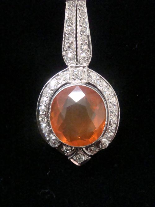 fig 1. An Edwardian 18ct white gold pendant necklace featuring two oval cut orange fire opals framed by small diamonds along an articulated geometric drop.