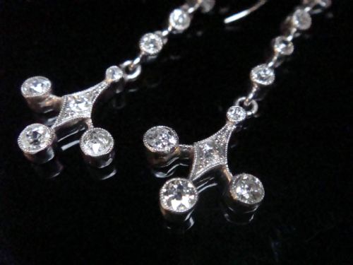 fig 1. Pair of Edwardian platinum drop earrings featuring articulated lines of bezel-set round old cut diamonds terminating in geometric drops with hook fastenings.