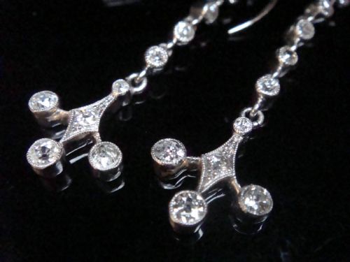 fig 2. Pair of Edwardian platinum drop earrings featuring articulated lines of bezel-set round old cut diamonds terminating in geometric drops with hook fastenings.