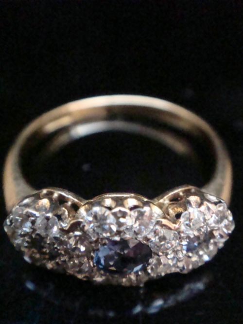 fig 1. An Edwardian 18ct yellow gold ring featuring three cluster mounts set with dark blue sapphires and surrounded by small diamonds.