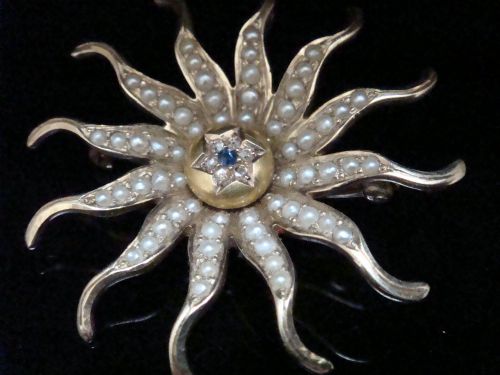 fig 1. An antique 14ct yellow gold starburst pendant brooch decorated with seed pearl rays around a central star setting with a sapphire and rose-cut diamonds.
