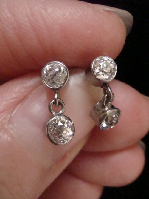 fig 1. Pair of Edwardian 18ct white gold drop earrings featuring rubover bezel-set old cut diamonds.