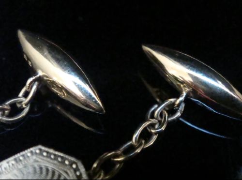 A pair of Edwardian cufflinks featuring octagonal platinum faces with engine-turned sunburst detailing and central old-cut diamonds, connected by chains to yellow gold torpedo backs. View V