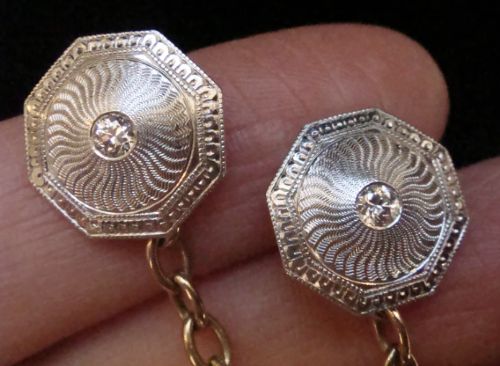 A pair of Edwardian cufflinks featuring octagonal platinum faces with engine-turned sunburst detailing and central old-cut diamonds, connected by chains to yellow gold torpedo backs. View VII