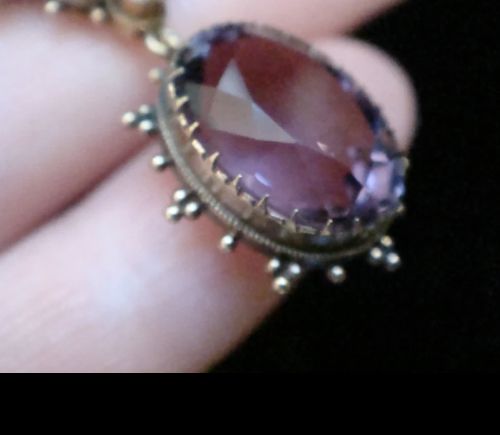fig 1. A Victorian 15ct yellow gold round pendant featuring a large faceted purple amethyst bordered by delicate seed pearl accents and granulated wirework.