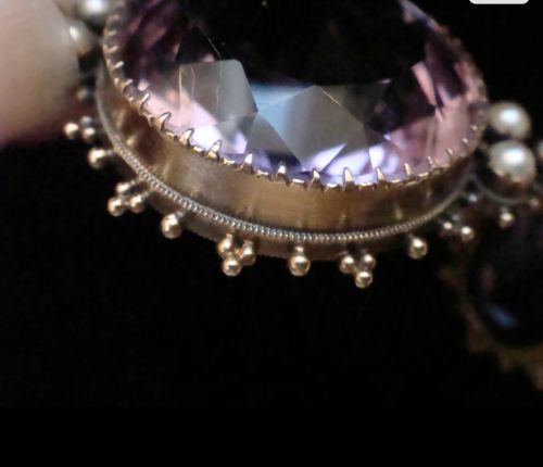 A Victorian 15ct yellow gold round pendant featuring a large faceted purple amethyst bordered by delicate seed pearl accents and granulated wirework. View III
