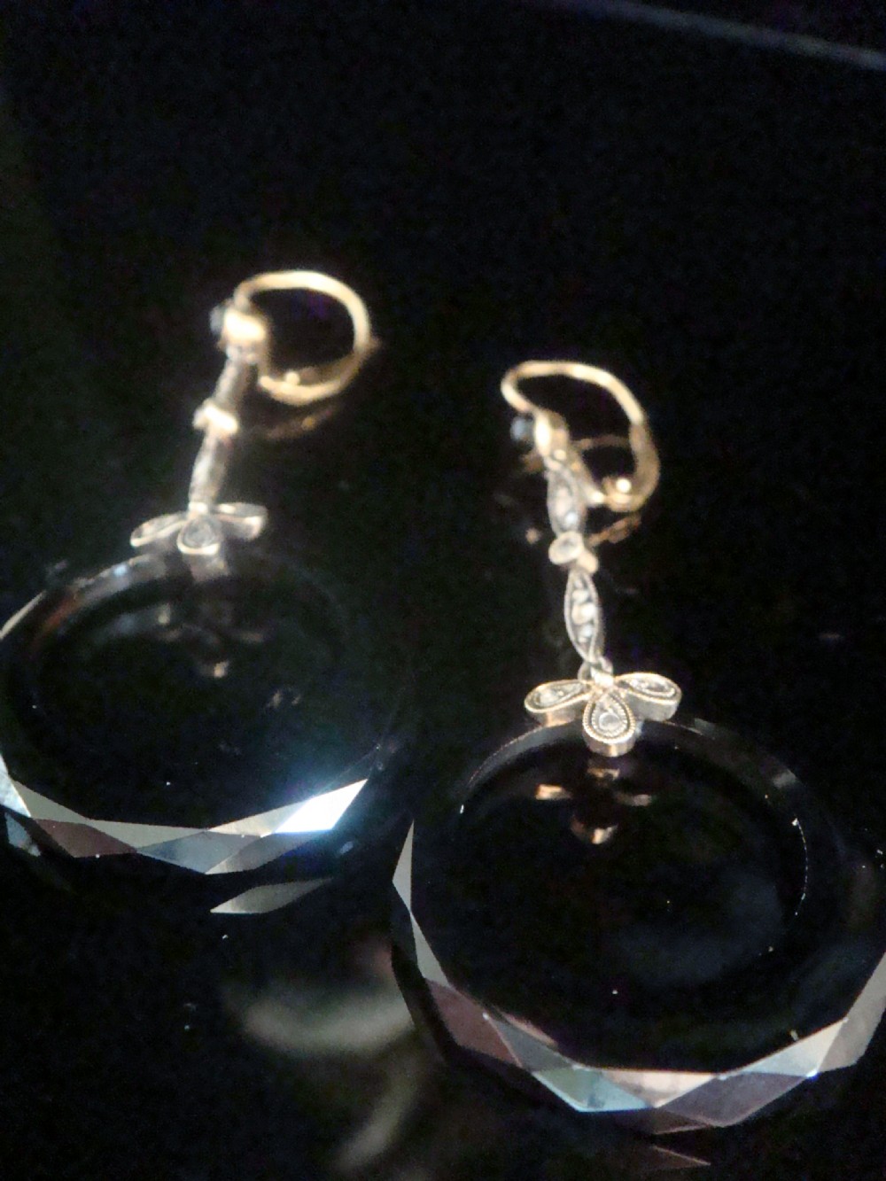 A pair of Edwardian drop earrings featuring faceted black onyx hoops suspended from diamond-set ribbon bow accents and articulated drops. View VI