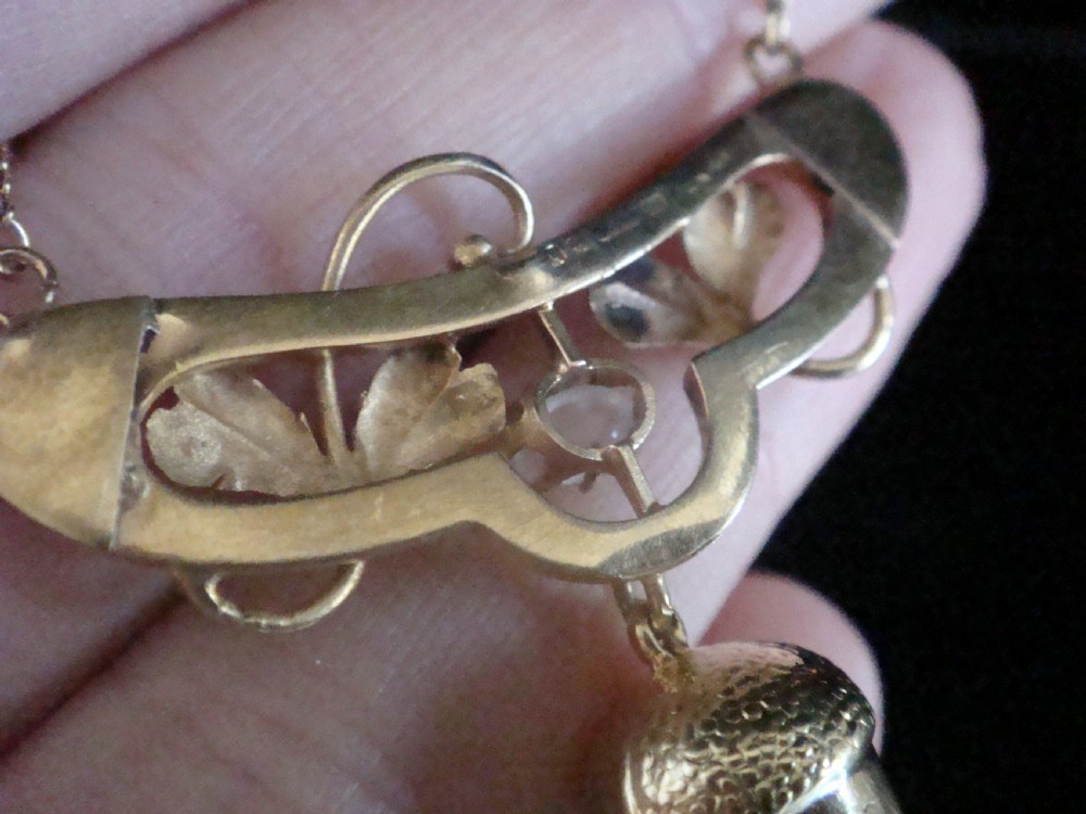 An Art Nouveau yellow gold necklace featuring a central oval moonstone, sculpted leaves, and a textured hanging acorn pendant. View II