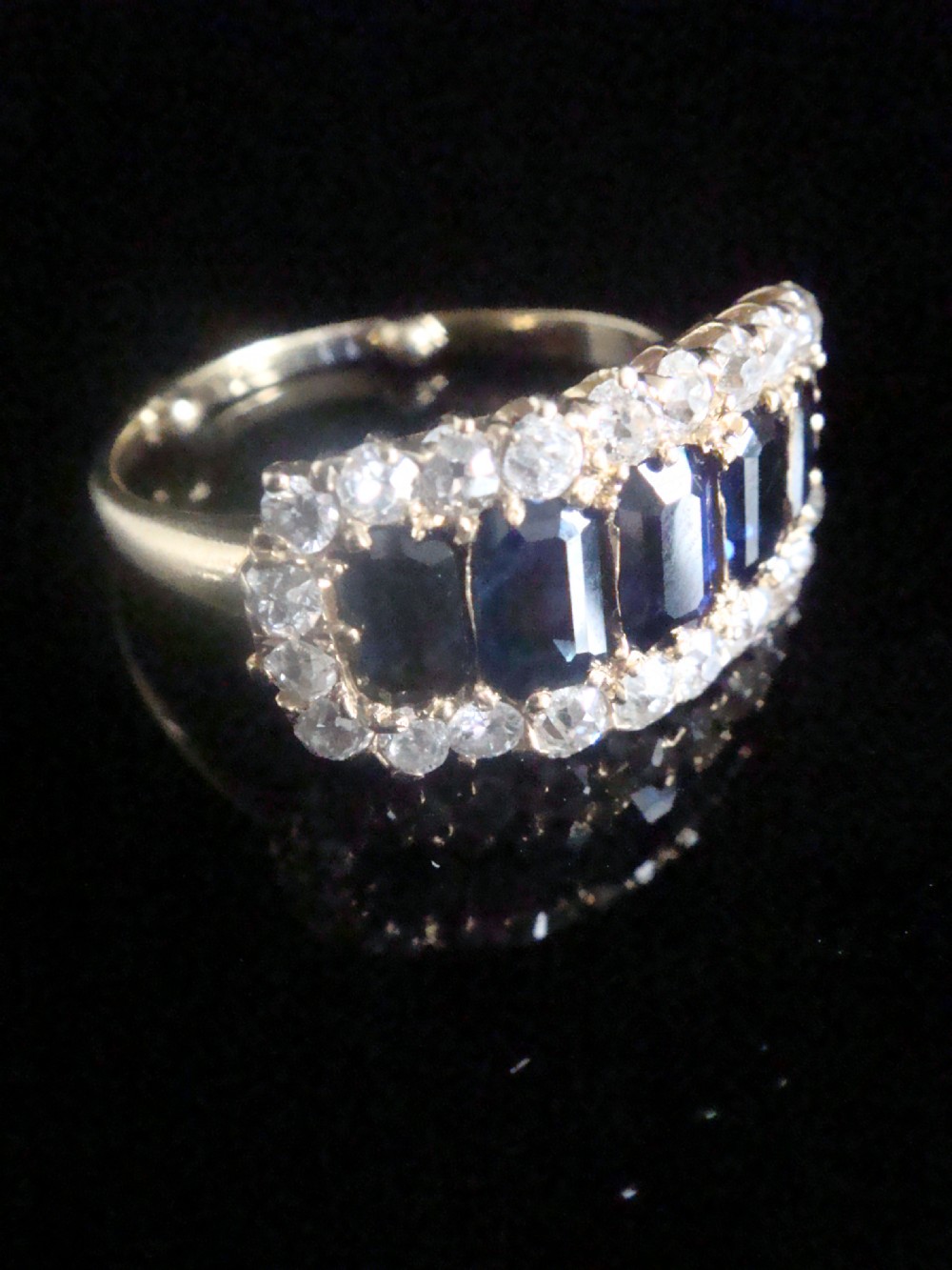 An 18ct yellow gold Victorian boat ring featuring central sapphires framed by a border of small round diamonds.