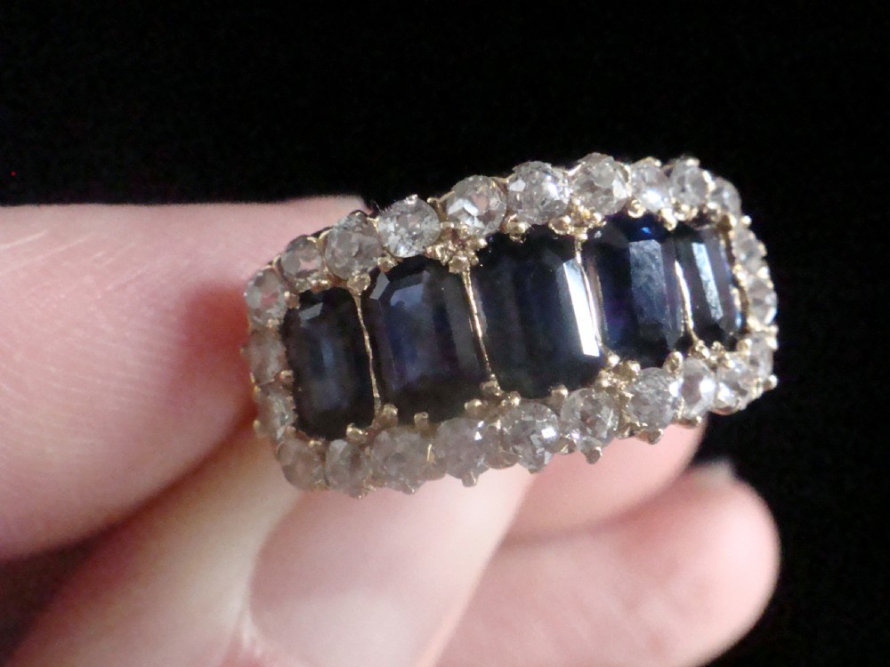 An 18ct yellow gold Victorian boat ring featuring central sapphires framed by a border of small round diamonds. View IV