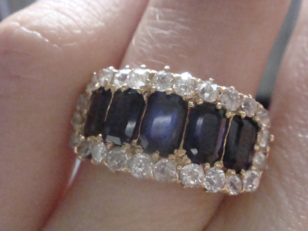 An 18ct yellow gold Victorian boat ring featuring central sapphires framed by a border of small round diamonds. View V