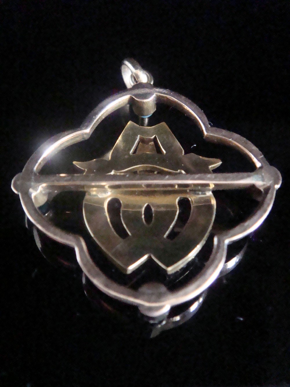 A Victorian gold pendant featuring two central intertwined hearts set with seed pearls within a quatrefoil border accented with four round turquoise stones. View III