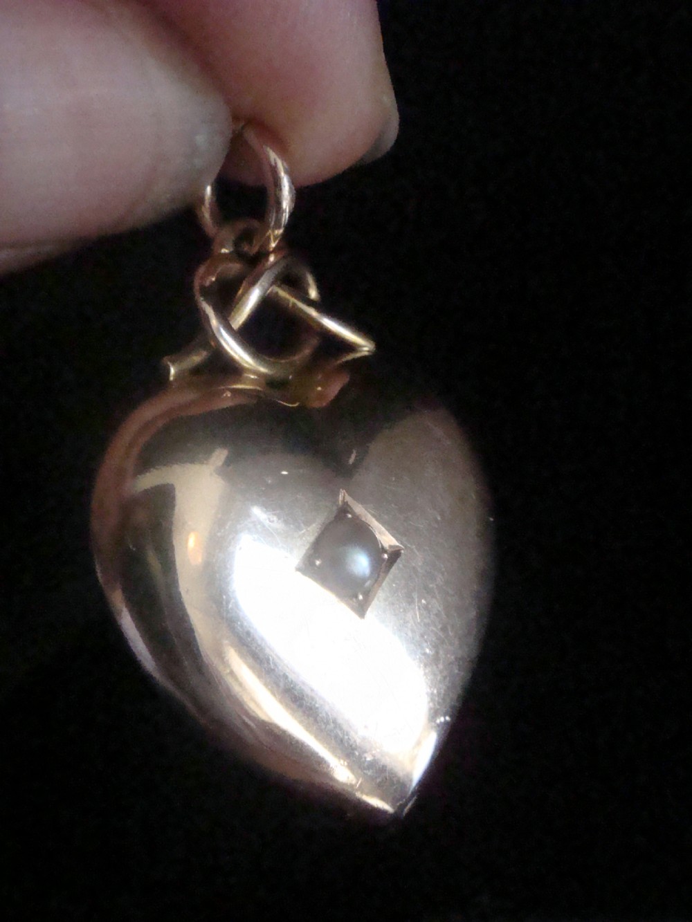 A Victorian 15ct yellow gold puffed heart pendant set with a central seed pearl in a diamond-shaped star setting.