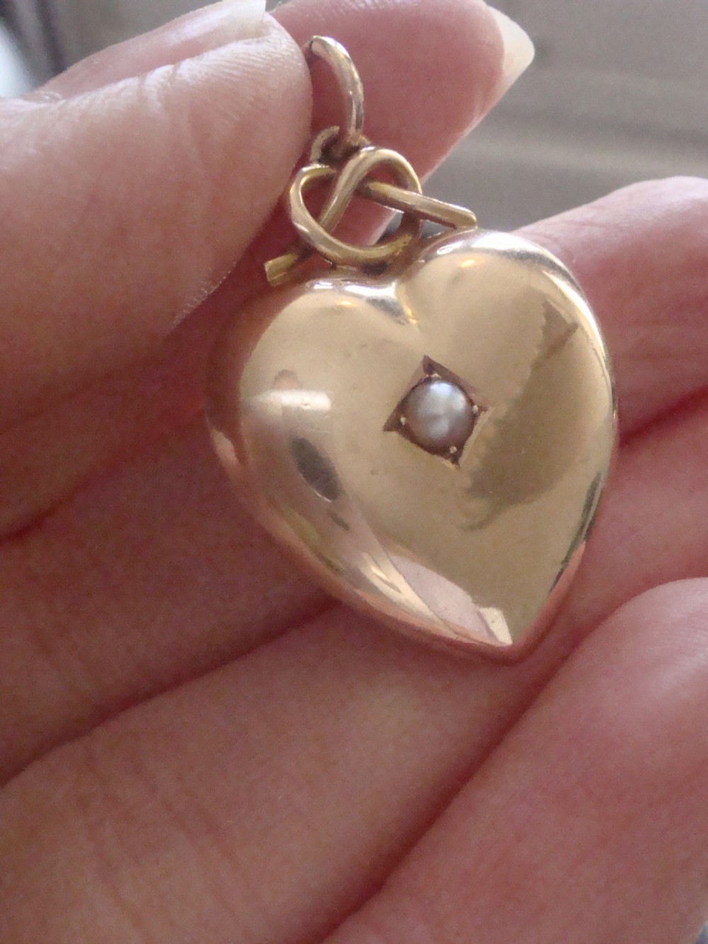 A Victorian 15ct yellow gold puffed heart pendant set with a central seed pearl in a diamond-shaped star setting. View II