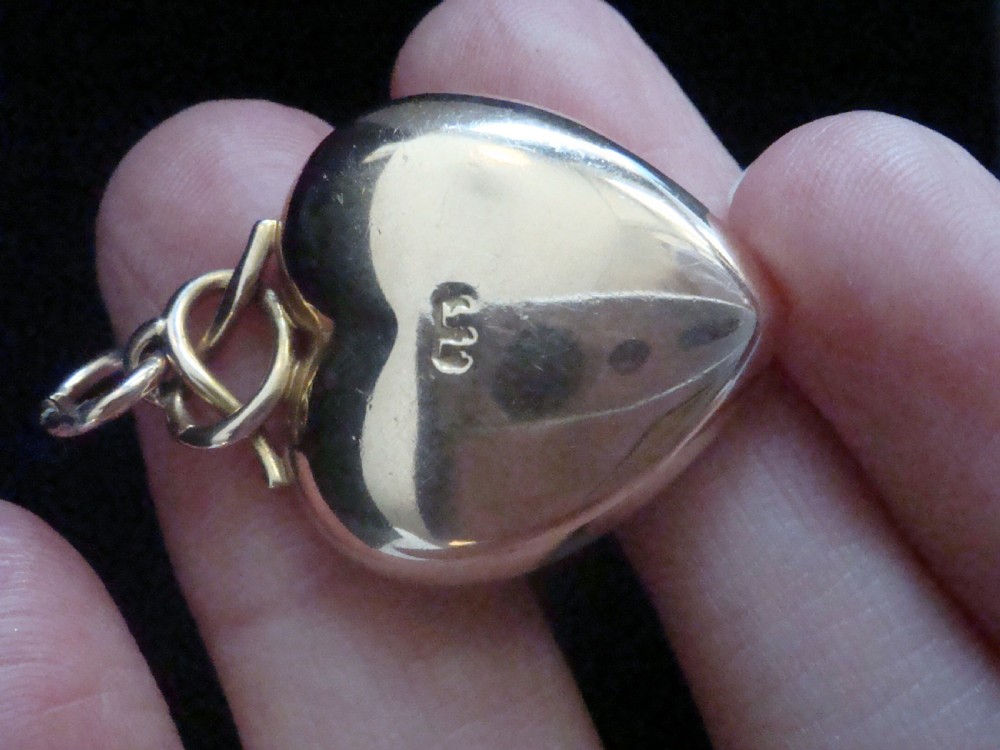 A Victorian 15ct yellow gold puffed heart pendant set with a central seed pearl in a diamond-shaped star setting. View IV