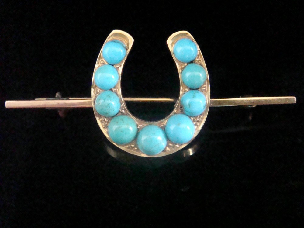 An Edwardian 15ct gold horseshoe brooch set with nine round turquoise cabochons mounted on a bar pin stem. View II
