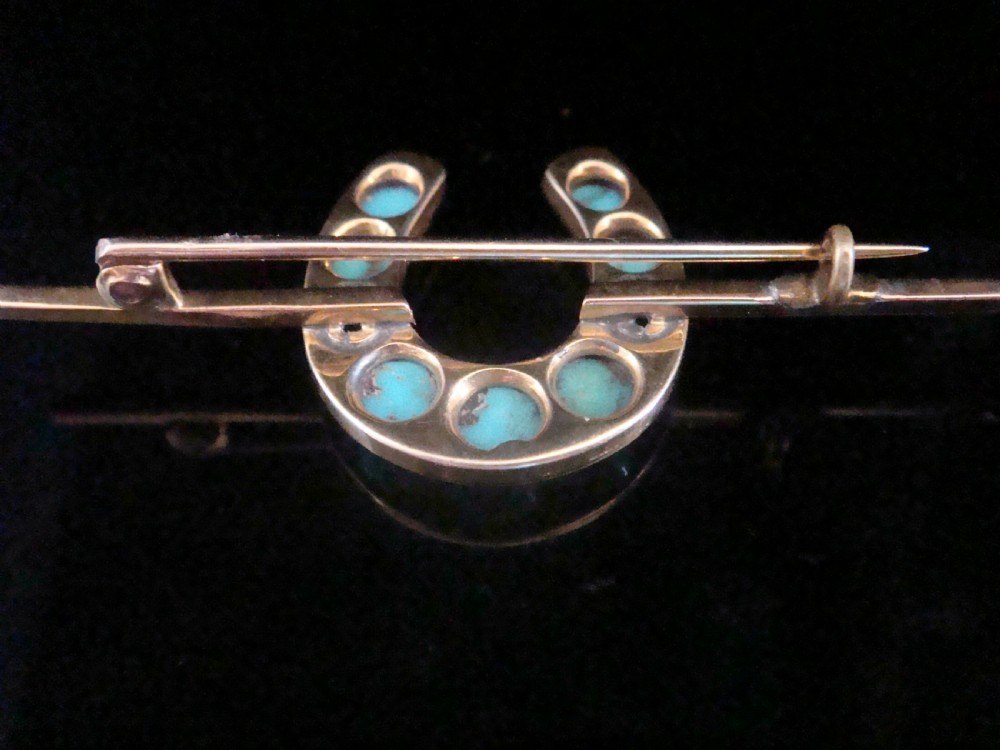 An Edwardian 15ct gold horseshoe brooch set with nine round turquoise cabochons mounted on a bar pin stem. View III