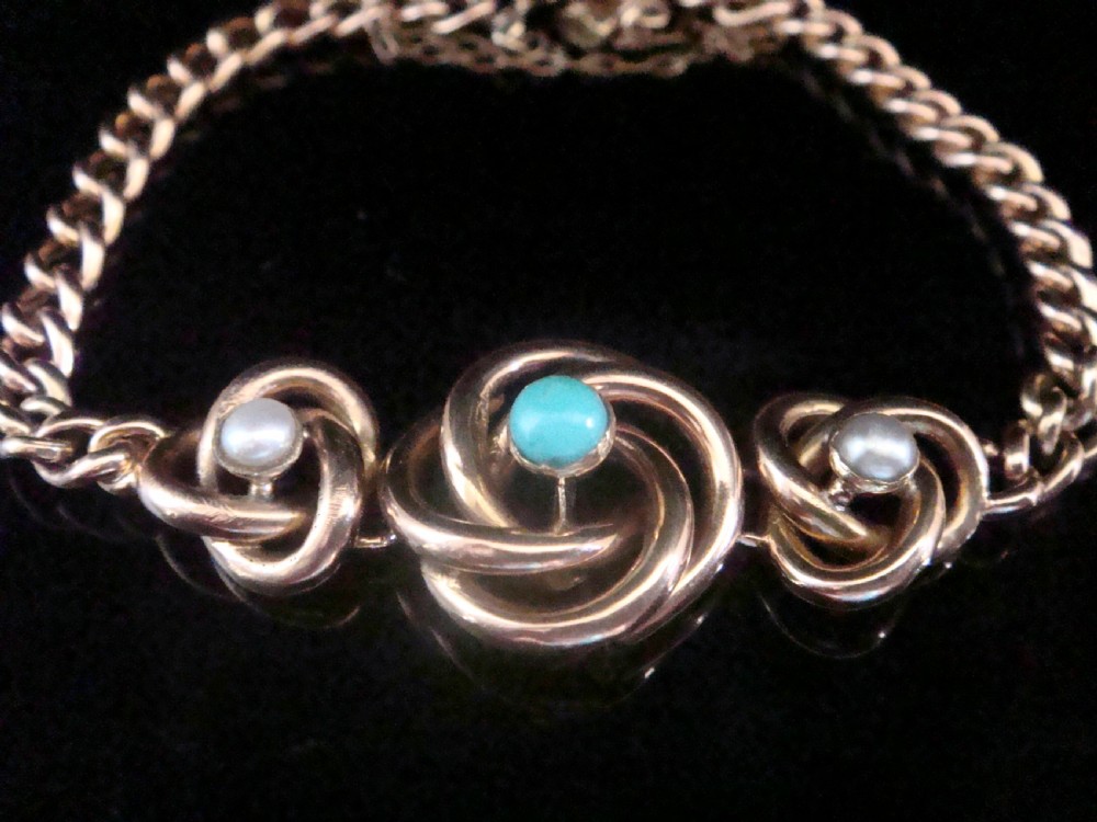 A Victorian 9ct rose gold curb chain bracelet featuring three central lovers knot motifs set with turquoise and seed pearls.