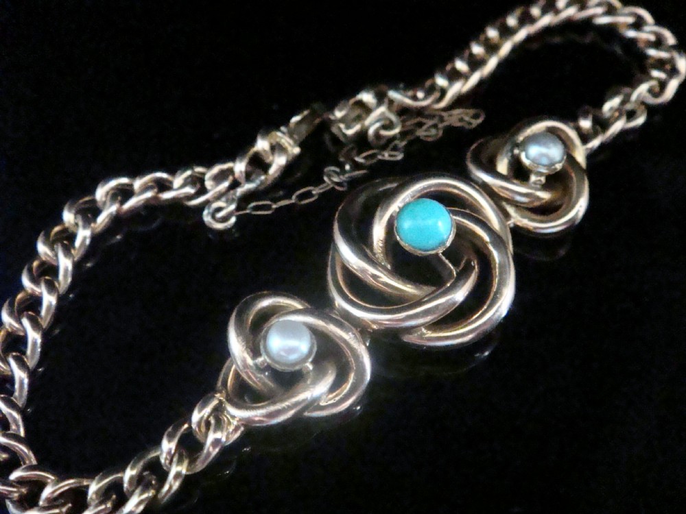 A Victorian 9ct rose gold curb chain bracelet featuring three central lovers knot motifs set with turquoise and seed pearls. View III