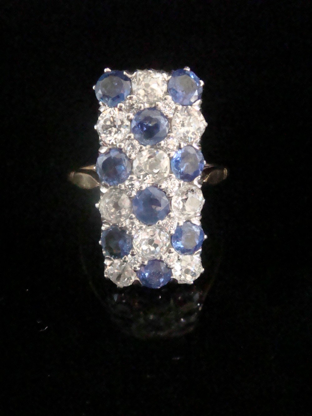 An Art Deco rectangular plaque dress ring featuring a grid setting of round blue sapphires and old cut diamonds set in platinum atop a gold band. View III
