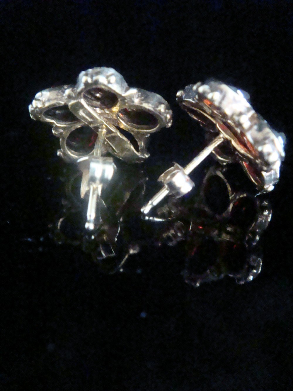 A pair of 1960s flower-shaped stud earrings featuring five smooth cabochon red garnets as petals surrounding a central white pearl, set in gold. View II
