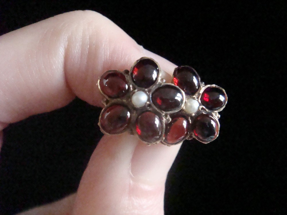 A pair of 1960s flower-shaped stud earrings featuring five smooth cabochon red garnets as petals surrounding a central white pearl, set in gold. View III