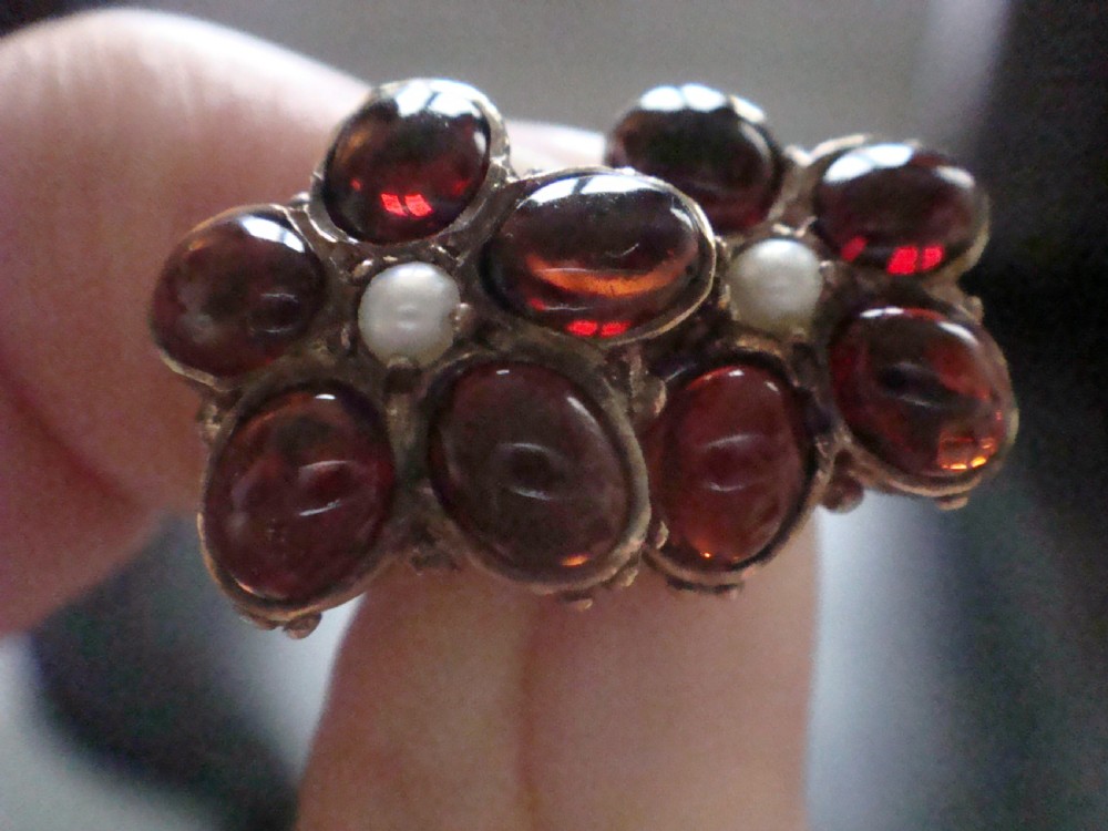 A pair of 1960s flower-shaped stud earrings featuring five smooth cabochon red garnets as petals surrounding a central white pearl, set in gold. View IV