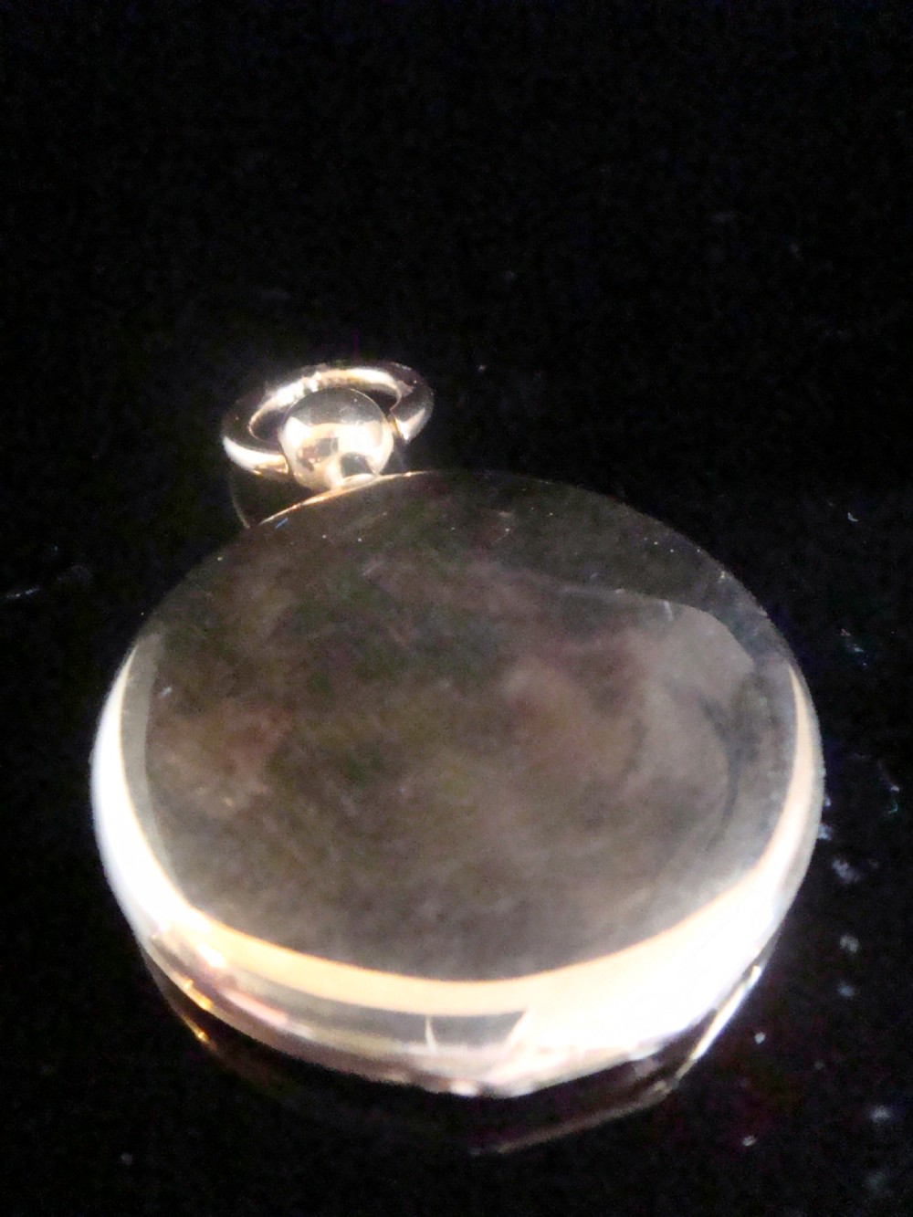 A round Victorian 15ct yellow gold locket shaped like a pocket watch with a top loop and glass compartment.