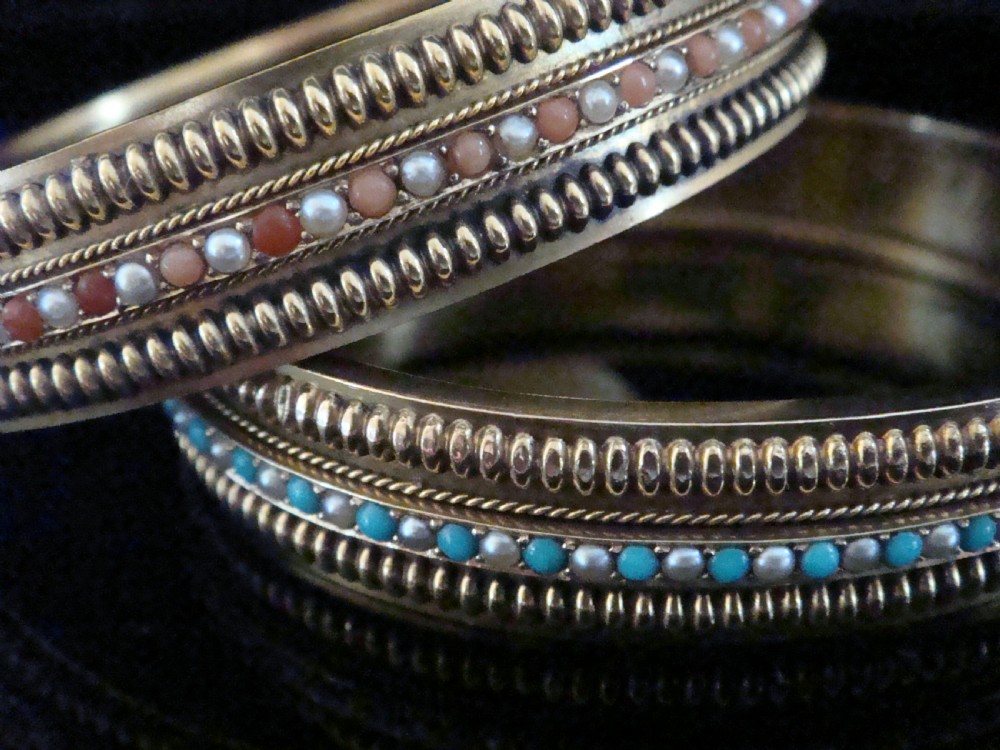 A pair of Victorian 15ct gold bangles featuring beaded borders and central rows of alternating seed pearls, coral, and turquoise cabochons.