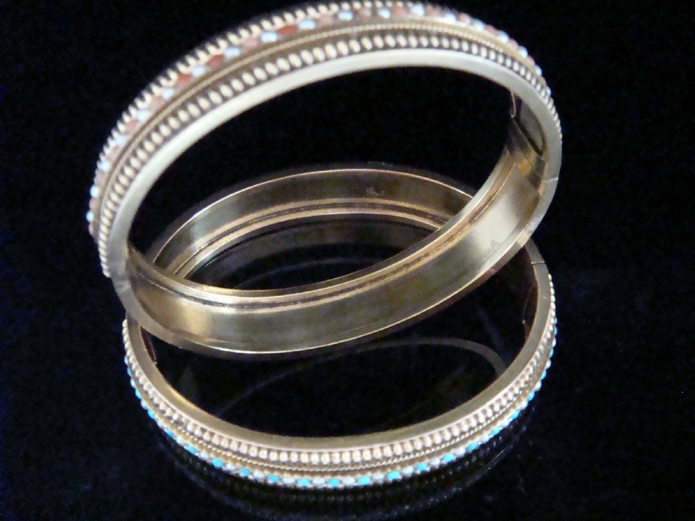 A pair of Victorian 15ct gold bangles featuring beaded borders and central rows of alternating seed pearls, coral, and turquoise cabochons. View VI