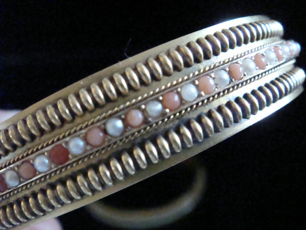 A pair of Victorian 15ct gold bangles featuring beaded borders and central rows of alternating seed pearls, coral, and turquoise cabochons. View VIII