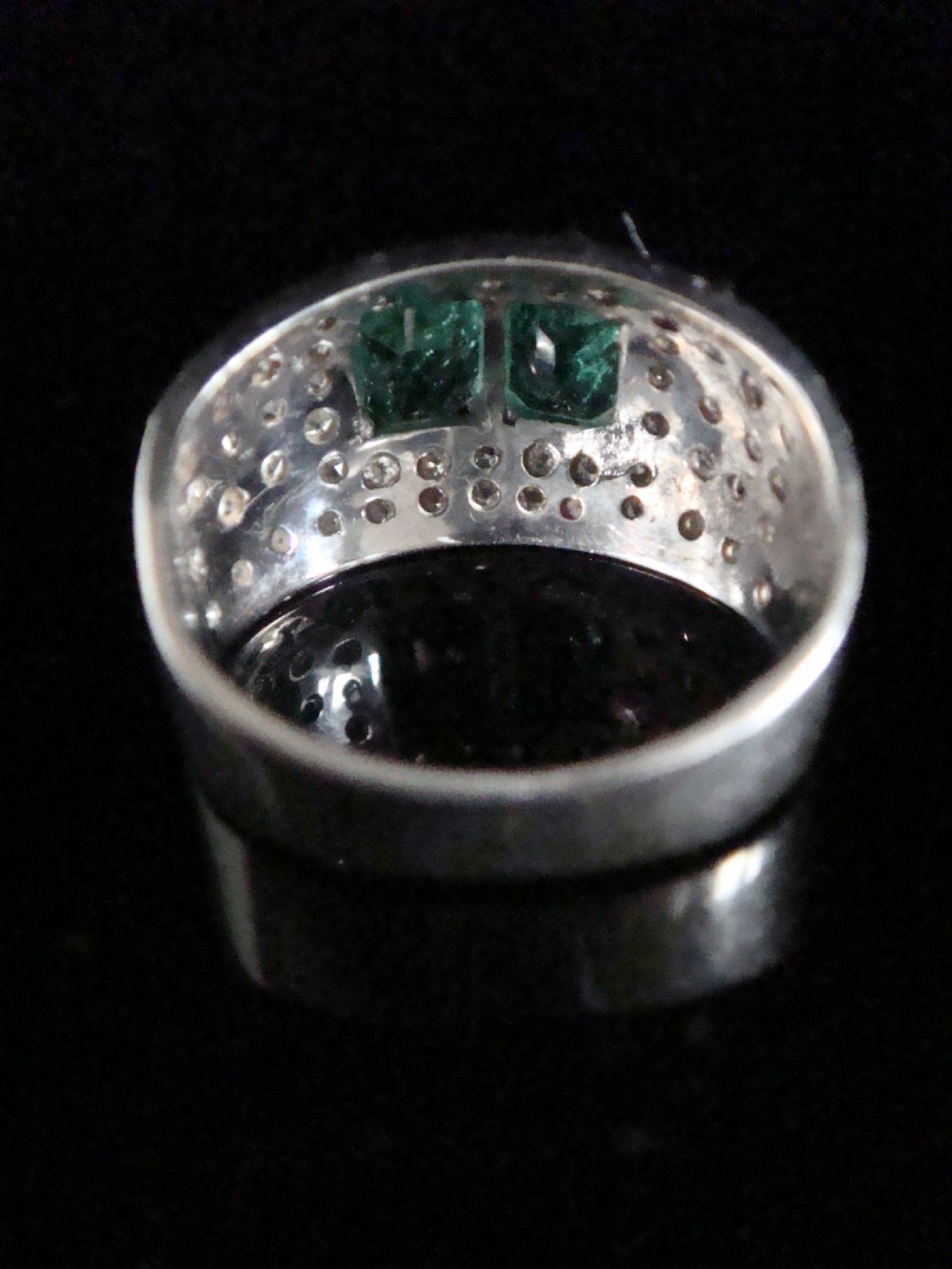 An Art Deco platinum band set with two central emerald-cut green emeralds framed by a broad pave diamond setting. View IV